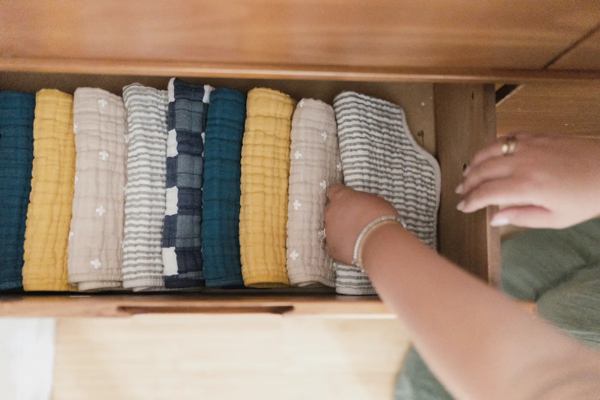 Neatly folded baby blankets being organized in a drawer