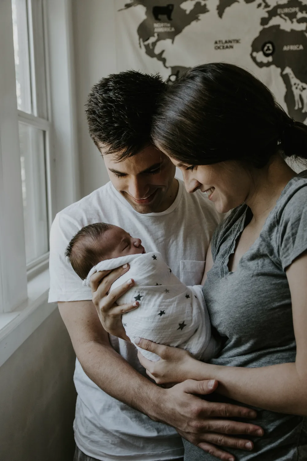 New parents smiling at their swaddled newborn together