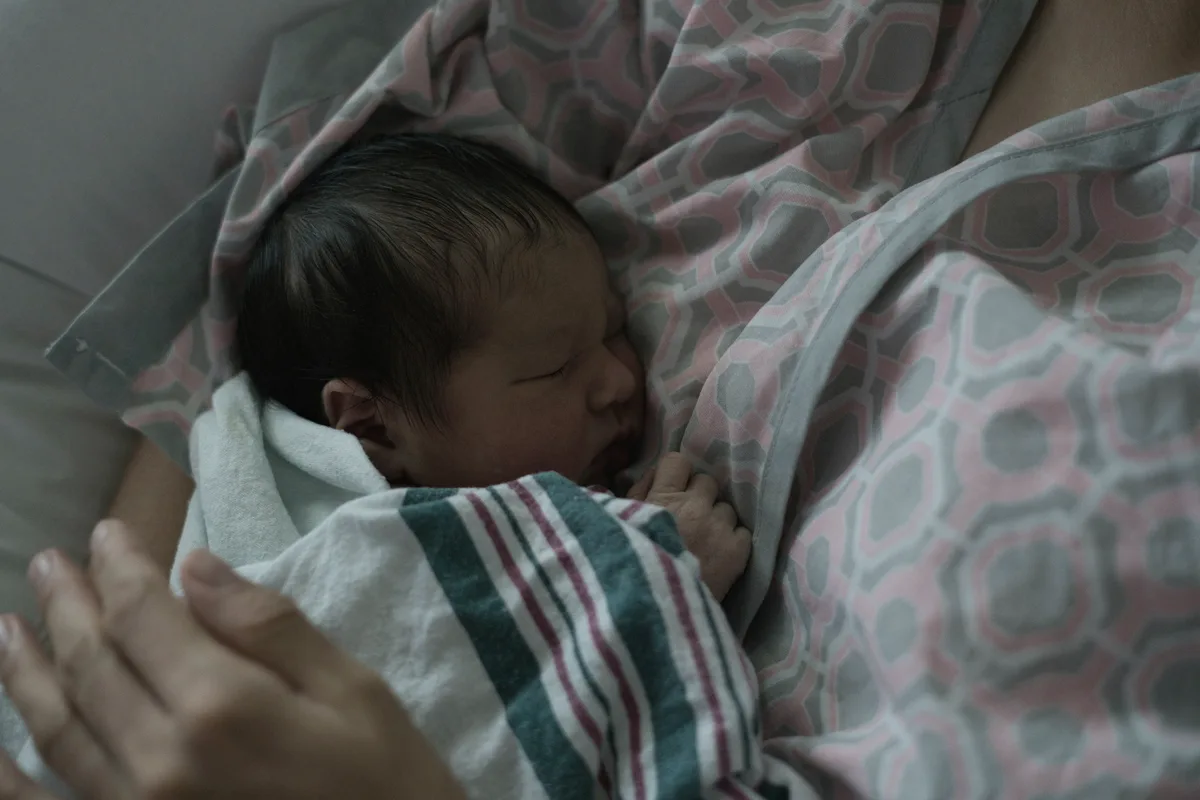 Mother resting while holding her sleeping newborn